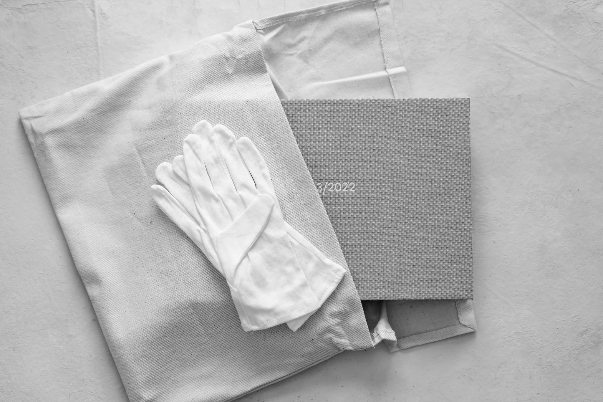 A linen album with white gloves draped over.