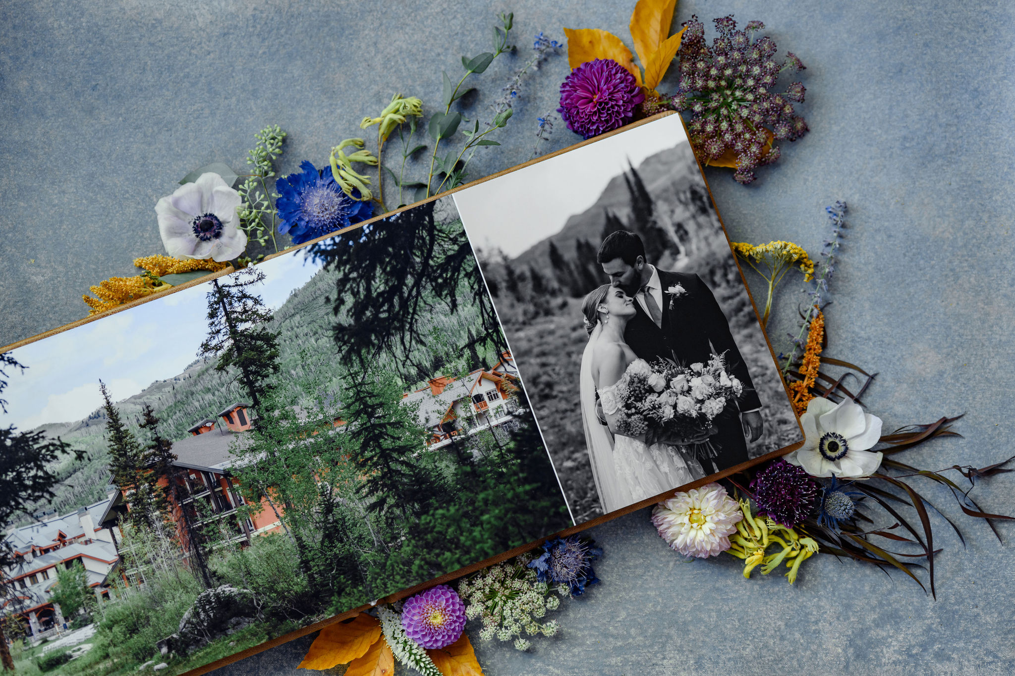 A leather bound wedding photo album surrounbded by fresh flowers.