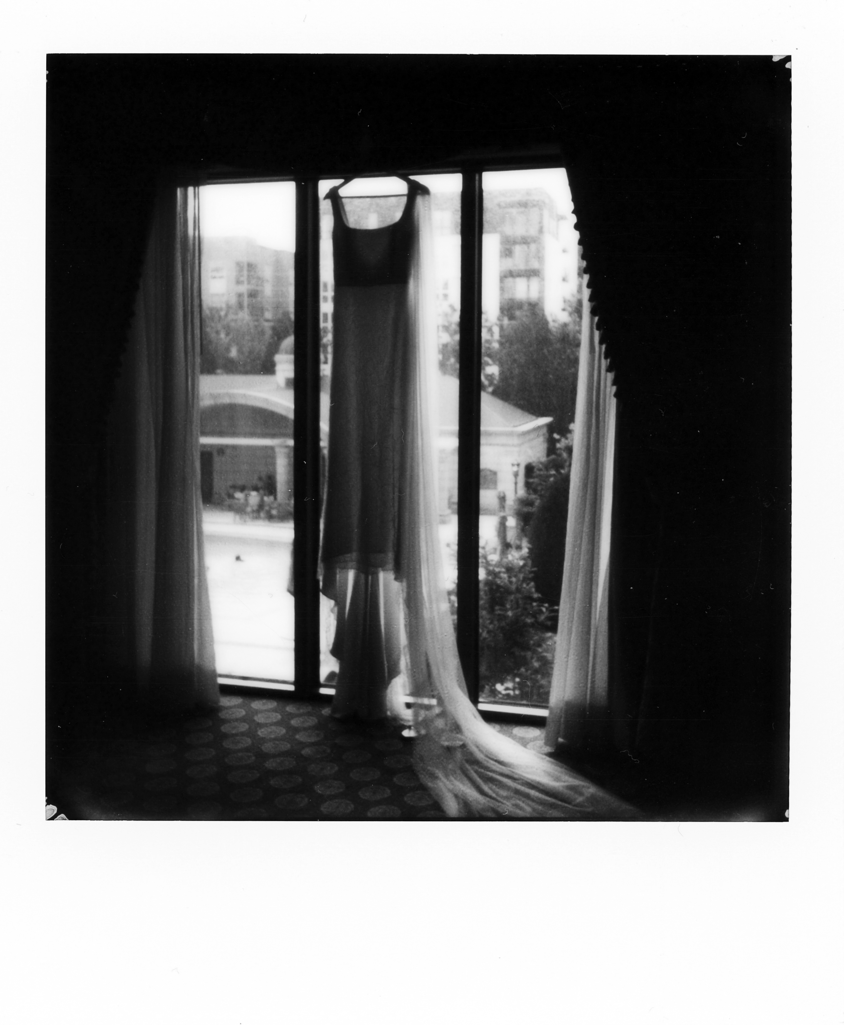 A wedding dress hung from a window to silhouette it.